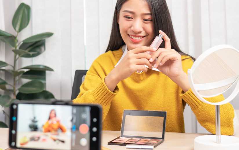 Smiling beauty influencer filming a makeup tutorial, highlighting affiliate marketing for creators in the cosmetics niche.